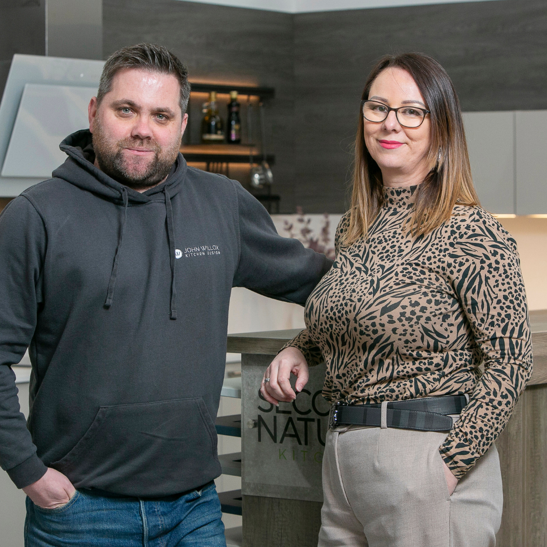 John and Elaine Willox, co-founders of John Willox Kitchen Design, standing together and smiling. Their team photo showcases the duo's commitment and passion for innovative kitchen design