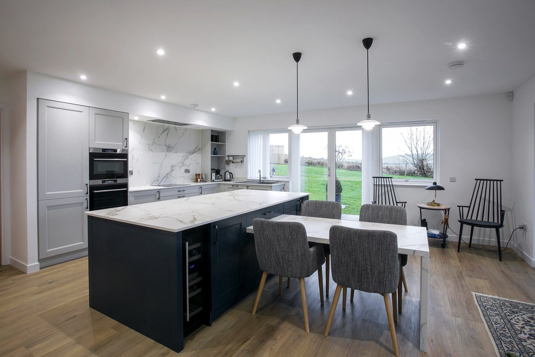 Grey shaker style kitchen with navy island and marble effect worktops and splashbacks. Designed by John Willox Kitchen Design.