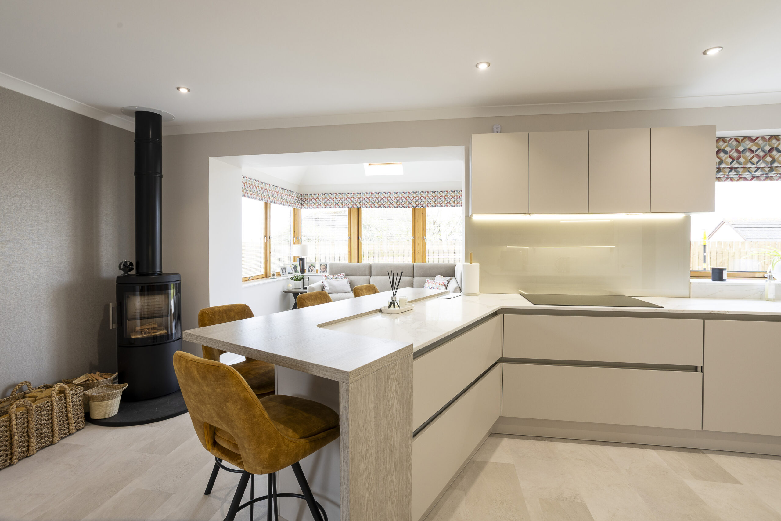 Breakfast Bar, LOog burner, view to the snug. Family Focused Kitchen, Warm neutrals, John Willox Kitchen Design, Ellon, Aberdeen. Facebook Schema Image